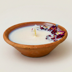 Lunis rose candle poured in a natural clay pot with white wax and dried rose petals along the edge.