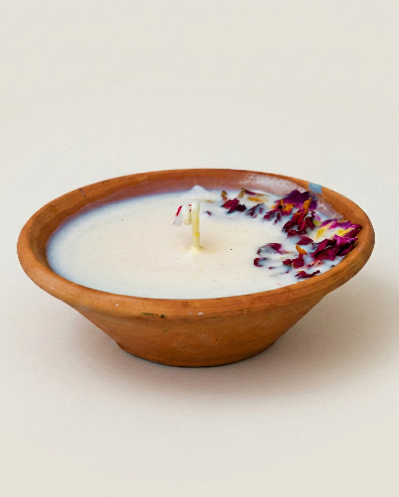 Lunis rose candle poured in a natural clay pot with white wax and dried rose petals along the edge.