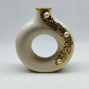Beige circular vase shaped candle decorated with gold glitter accents and pearl embellishments.