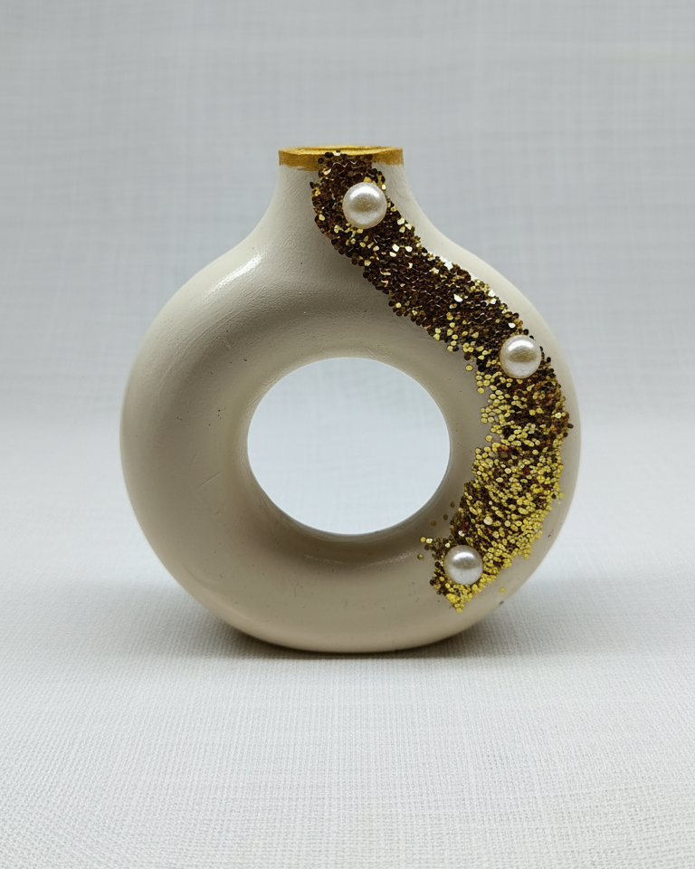 Beige circular vase shaped candle decorated with gold glitter accents and pearl embellishments.