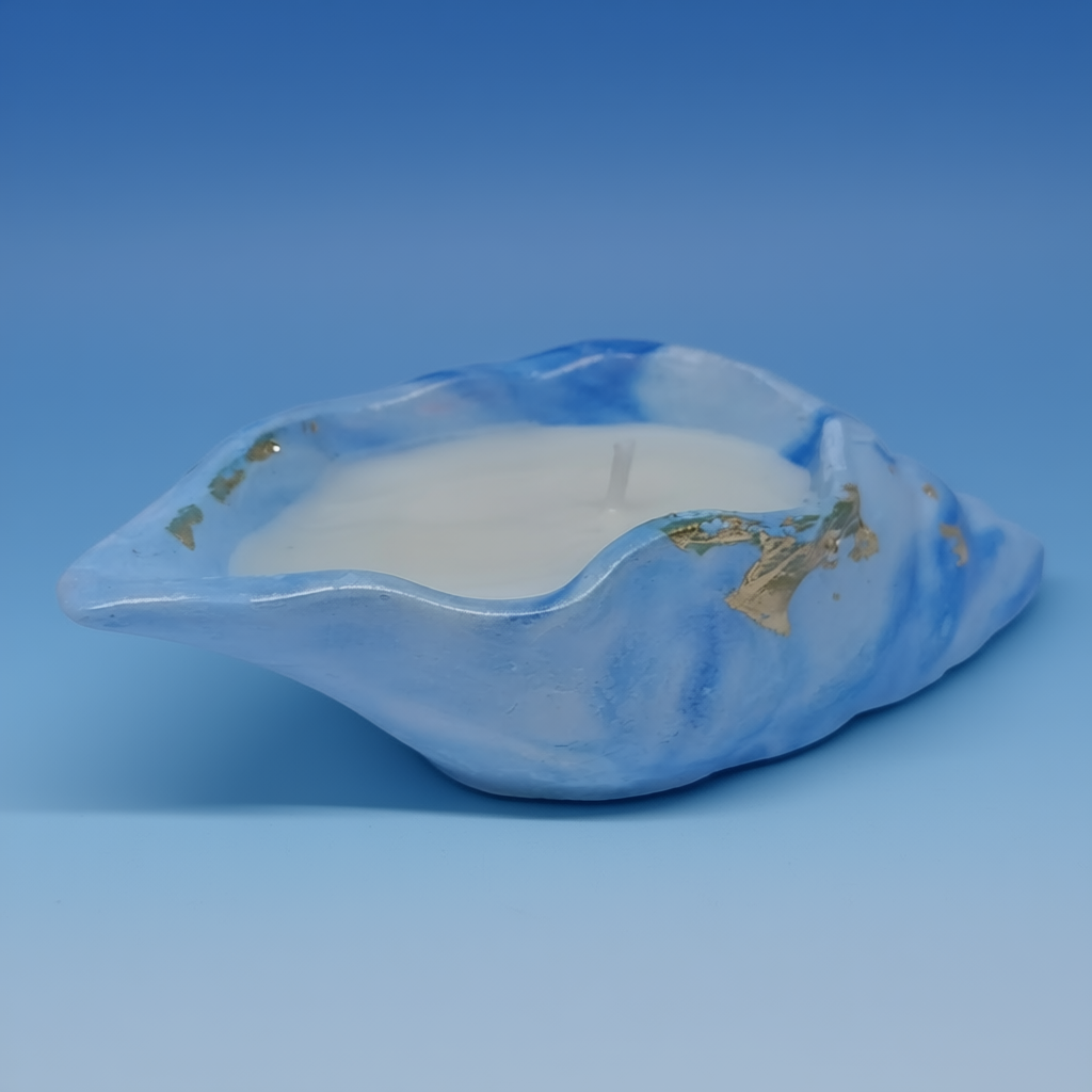 “Handcrafted blue shell-shaped scented candle with white wax and gold accents, placed against a soft light background.
