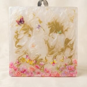 A handcrafted resin key holder with white and gold marble texture, pink floral border, and butterfly accents, featuring three gold hooks.