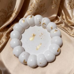 White cloud shaped concrete trinket dish with scattered gold leaf accents on a textured fabric background.