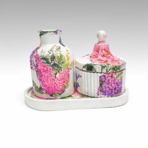 A handcrafted white concrete jar and vase set decorated with vibrant pink and purple floral designs placed on a matching oval tray.